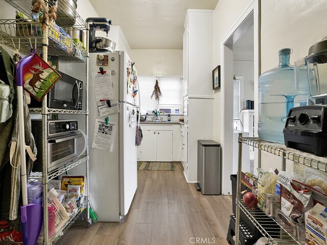 1407 Obispo Ave, Long Beach, CA 90804 - kitchen with freestanding refrigerator, white cabinetry, wood finished floors, and black microwave