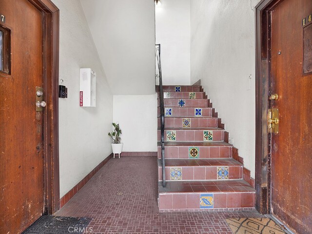 1407 Obispo Ave, Long Beach, CA 90804 - staircase featuring baseboards, brick patterned flooring, and vaulted ceiling