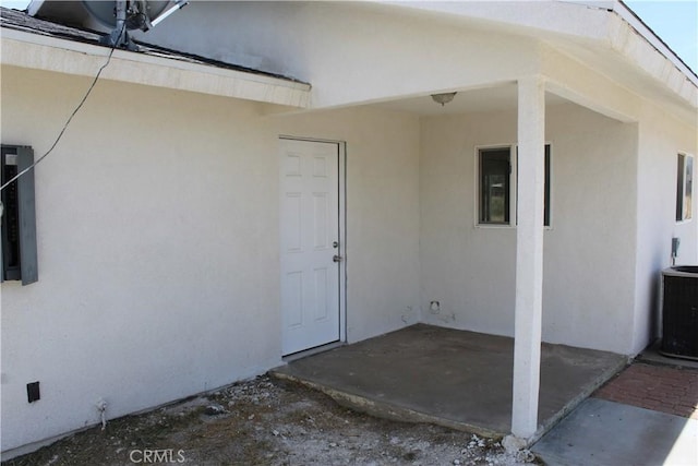 property entrance with a patio, central AC, and stucco siding