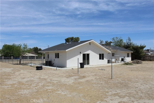 rear view of house featuring stucco siding and fence