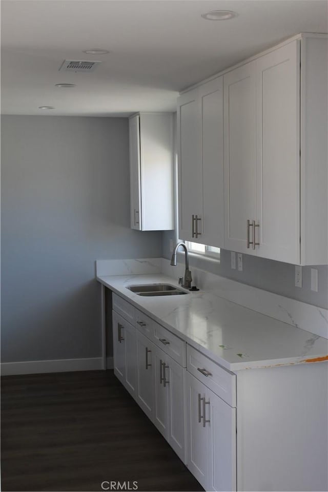 kitchen featuring white cabinets, dark wood-style flooring, baseboards, and a sink