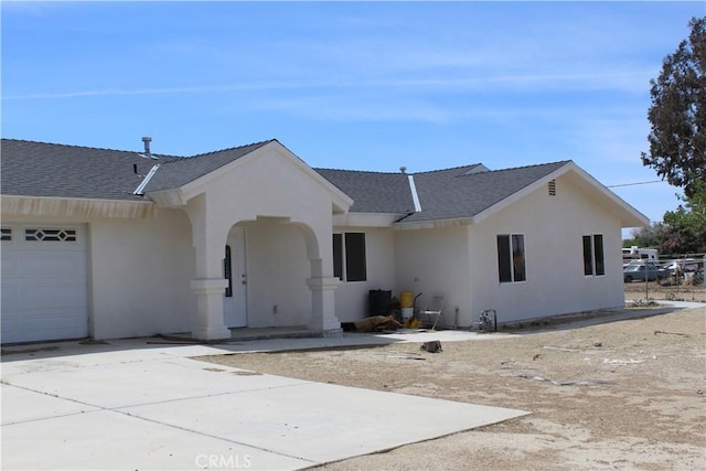 ranch-style house with a garage, stucco siding, and a shingled roof