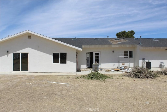 rear view of house with roof with shingles and stucco siding