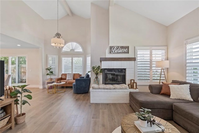 living room with high vaulted ceiling, light wood finished floors, beamed ceiling, baseboards, and a brick fireplace