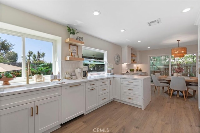 kitchen with open shelves, light wood-style floors, recessed lighting, a sink, and hanging light fixtures