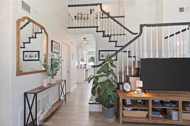 entrance foyer featuring stairs, wood finished floors, and a towering ceiling