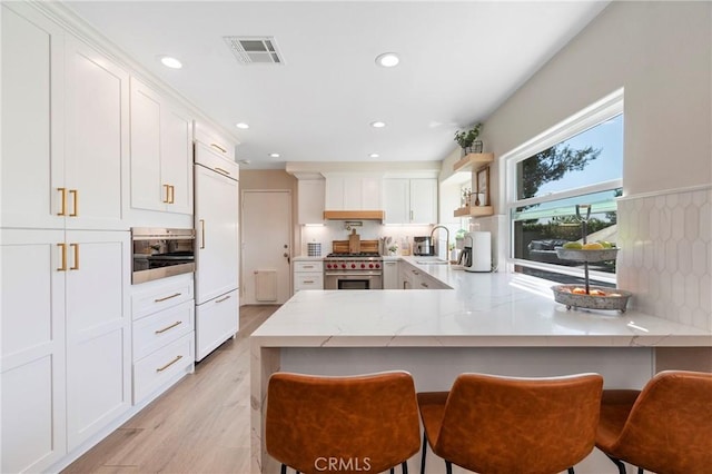 11691 Mount Baker Ct, Rancho Cucamonga, CA 91737 - kitchen with premium appliances, a peninsula, light stone counters, recessed lighting, and a sink