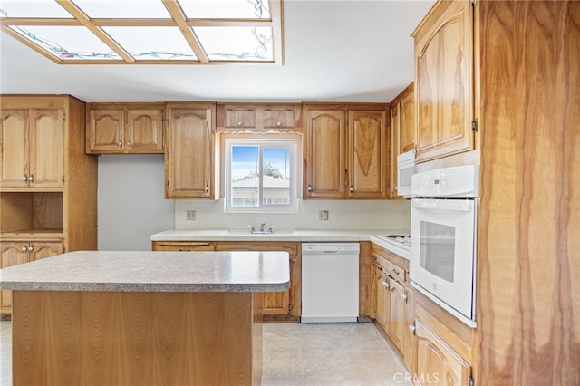 kitchen featuring white appliances, a center island, tasteful backsplash, a sink, and a skylight
