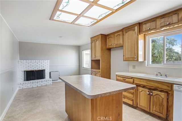 kitchen with white dishwasher, a sink, a fireplace, backsplash, and a kitchen island