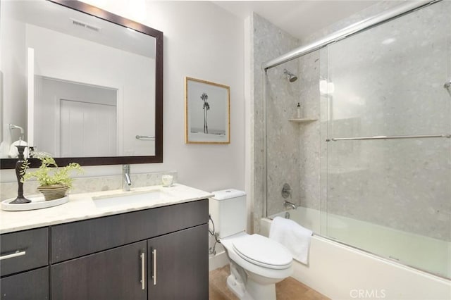 bathroom with toilet, visible vents, shower / bath combination with glass door, and vanity
