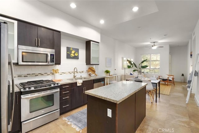 kitchen with dark brown cabinetry, a sink, a center island, stainless steel appliances, and decorative backsplash