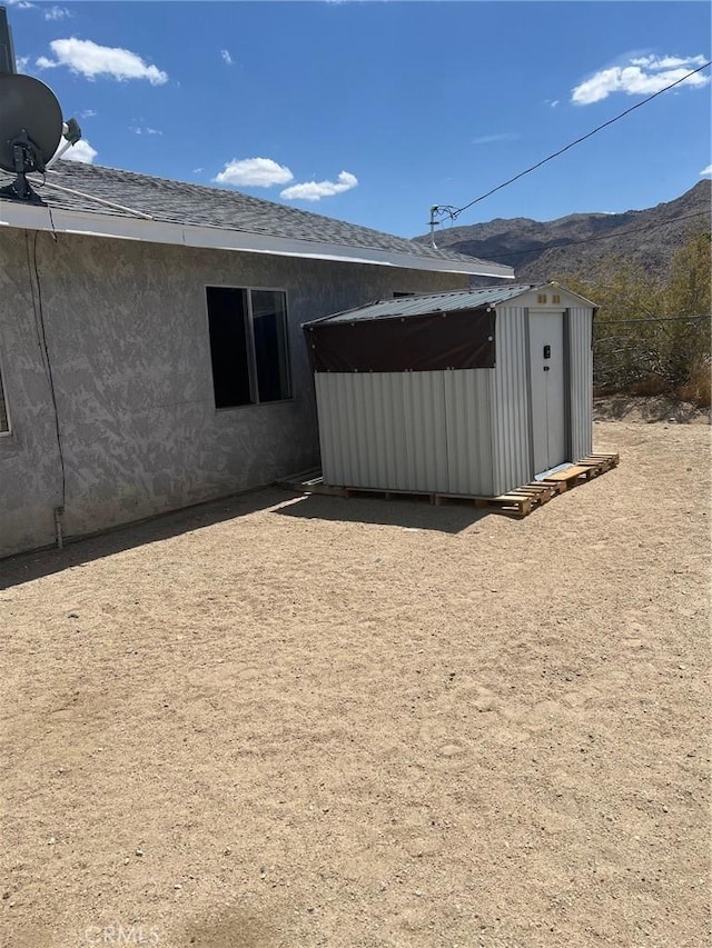 rear view of house featuring an outbuilding, a mountain view, and a shed