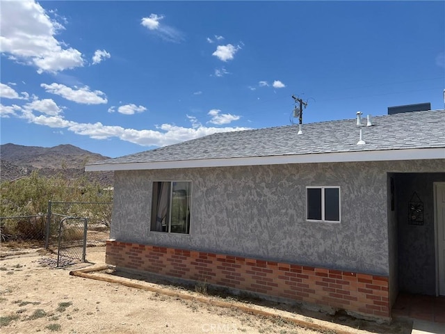 view of side of property featuring fence, a mountain view, and stucco siding