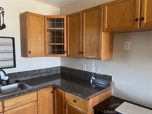 6614 Mojave Ave Unit 29, Palms, CA 92277 - kitchen with brown cabinetry, glass insert cabinets, and a textured wall