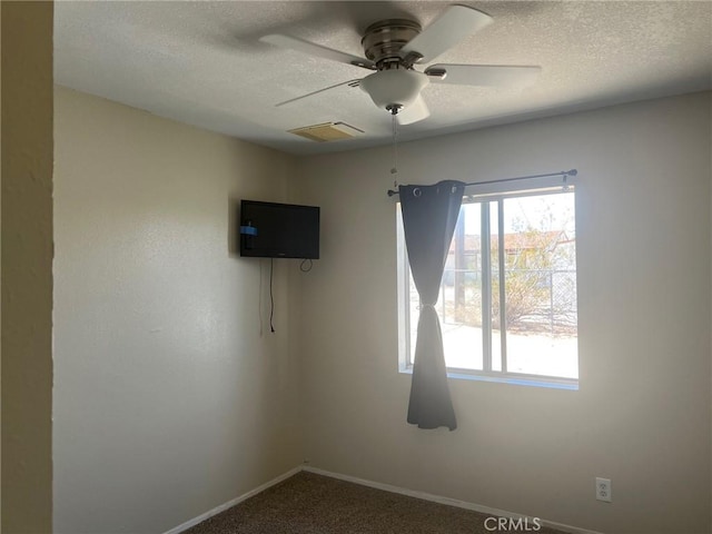 carpeted spare room with visible vents, a textured ceiling, baseboards, and ceiling fan