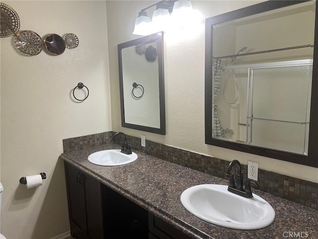 bathroom with double vanity, a sink, and a shower with shower door