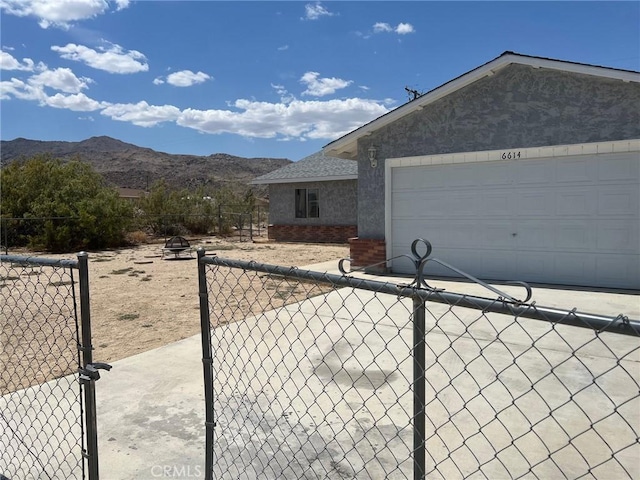 view of property exterior with fence, a garage, a gate, a mountain view, and concrete driveway