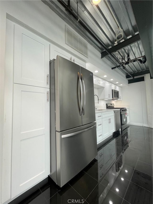 420 S San Pedro St Unit 102, Los Angeles, CA 90013 - kitchen featuring stainless steel appliances, white cabinetry, baseboards, dark tile patterned floors, and a sink