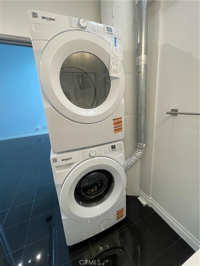 420 S San Pedro St Unit 102, Los Angeles, CA 90013 - laundry area featuring stacked washing machine and dryer, dark tile patterned floors, and baseboards