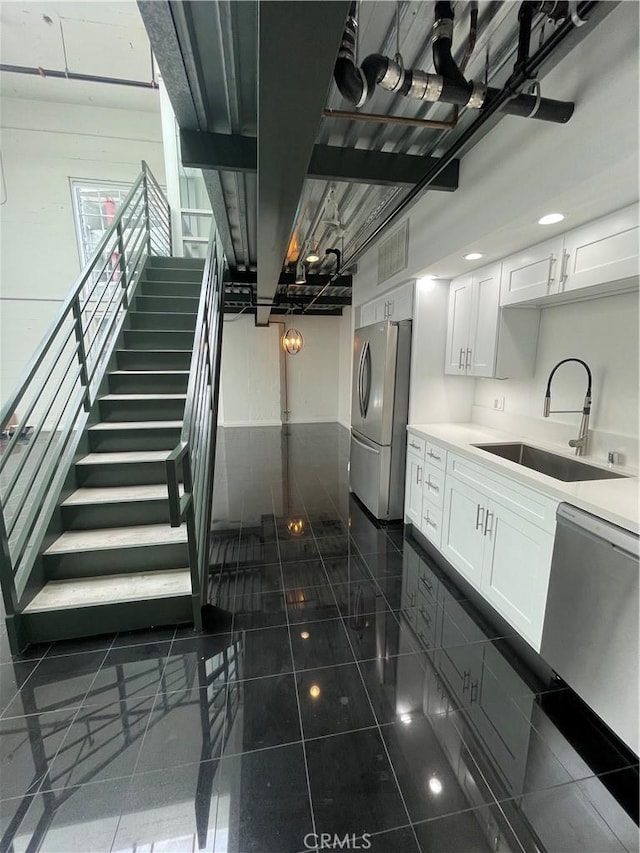 420 S San Pedro St Unit 102, Los Angeles, CA 90013 - kitchen with a sink, appliances with stainless steel finishes, white cabinetry, light countertops, and dark tile patterned flooring