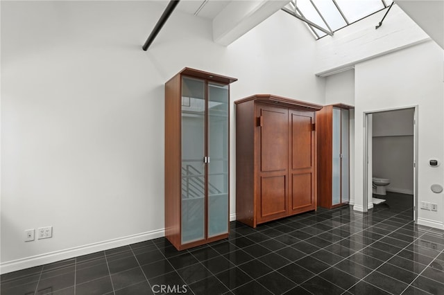420 S San Pedro St Unit 102, Los Angeles, CA 90013 - unfurnished bedroom featuring a skylight, dark tile patterned flooring, and a high ceiling