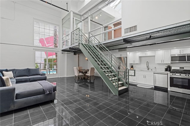 420 S San Pedro St Unit 102, Los Angeles, CA 90013 - living area with a towering ceiling, stairs, and dark tile patterned floors