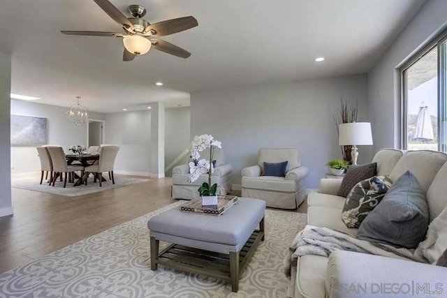 living room featuring recessed lighting, baseboards, wood finished floors, and ceiling fan with notable chandelier