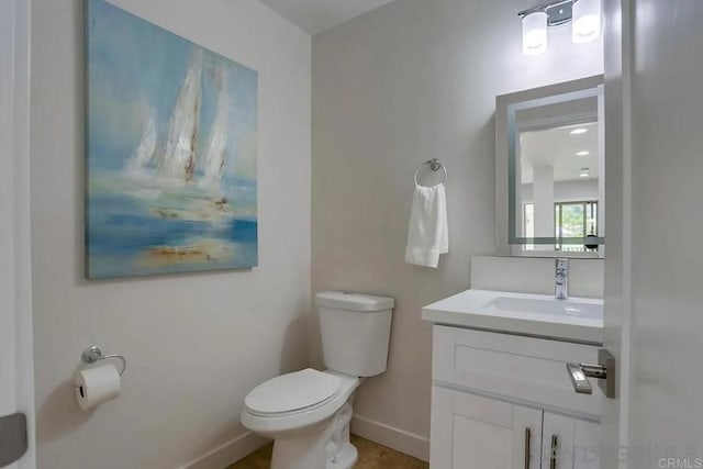 bathroom with baseboards, toilet, and vanity