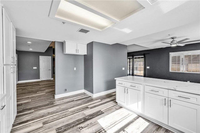 58957 Pueblo Trl, Yucca Valley, CA 92284 - kitchen with visible vents, light stone countertops, baseboards, white cabinets, and light wood finished floors