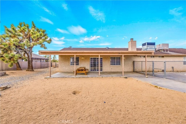58957 Pueblo Trl, Yucca Valley, CA 92284 - rear view of house featuring a chimney, a gate, a patio area, and stucco siding