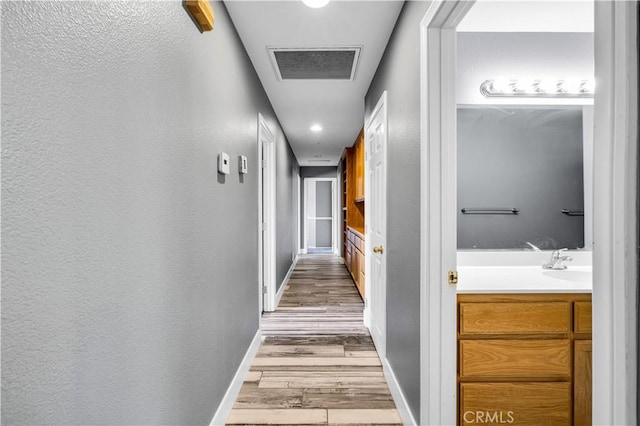 58957 Pueblo Trl, Yucca Valley, CA 92284 - hall with visible vents, a sink, baseboards, and wood finished floors