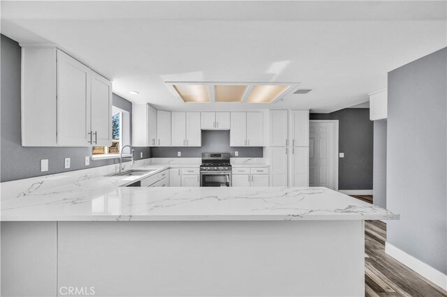 58957 Pueblo Trl, Yucca Valley, CA 92284 - kitchen with a peninsula, wood finished floors, light stone countertops, gas range, and a sink