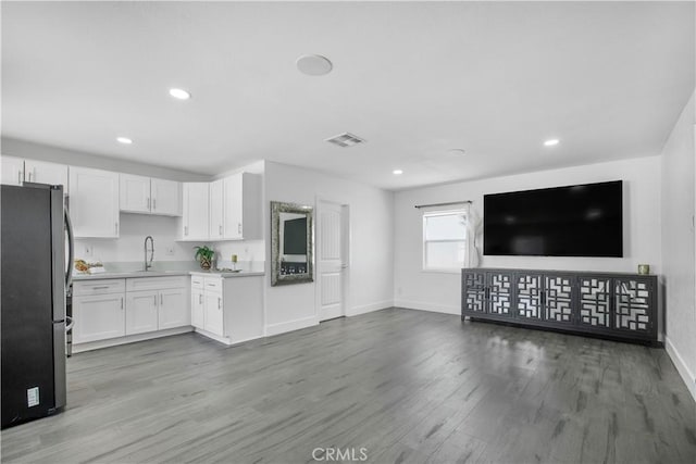 kitchen featuring visible vents, freestanding refrigerator, baseboards, white cabinets, and light wood finished floors