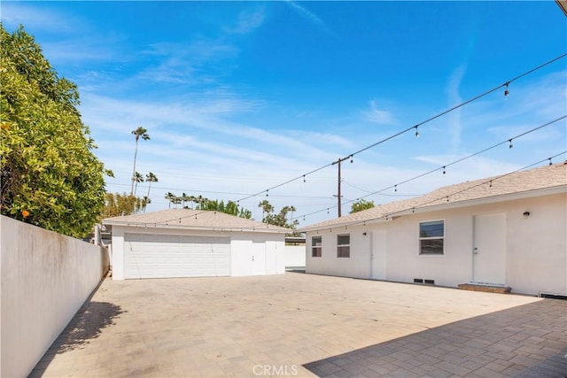 back of property with stucco siding, fence, an outbuilding, and a garage