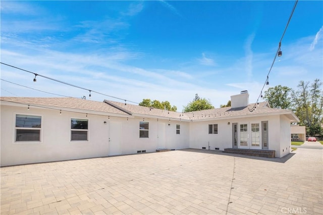 back of property featuring a chimney, french doors, a patio, and stucco siding