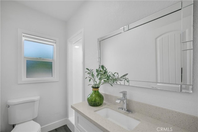 bathroom featuring toilet, baseboards, and vanity