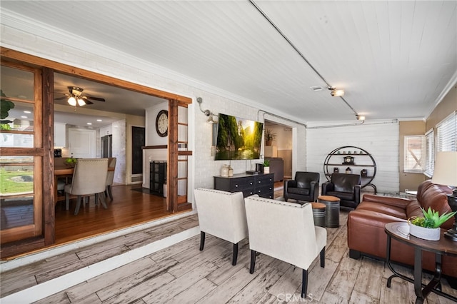 living room with crown molding, ceiling fan, a fireplace, and wood finished floors