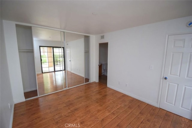 unfurnished bedroom with baseboards, hardwood / wood-style flooring, and visible vents