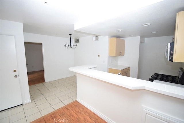 kitchen featuring visible vents, stainless steel microwave, a notable chandelier, and black gas range