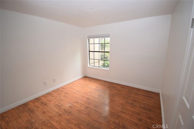 empty room featuring baseboards and hardwood / wood-style flooring