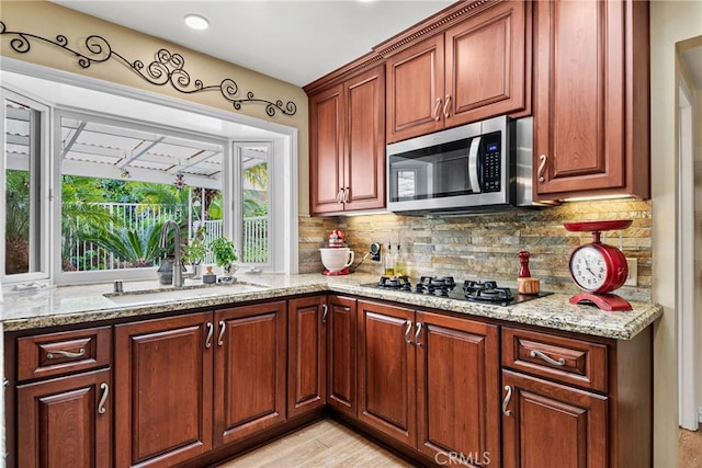 1528 E San Alto Ave, Orange, CA 92865 - kitchen featuring decorative backsplash, light stone countertops, stainless steel microwave, a sink, and black gas stovetop