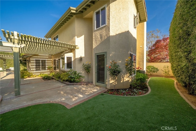back of property with fence, a pergola, a patio, stucco siding, and a yard
