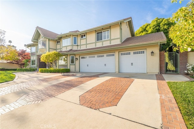 front facade with stucco siding, an attached garage, driveway, and a tile roof