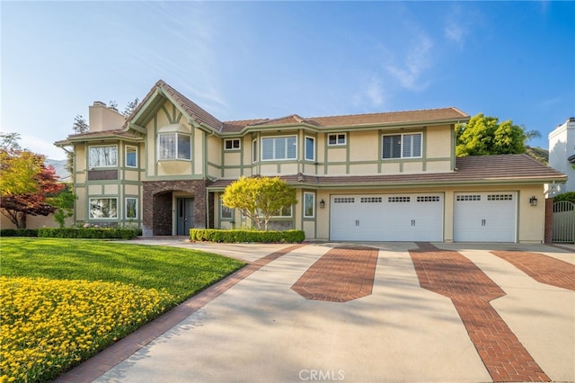 view of front of home featuring a front yard, stucco siding, a chimney, an attached garage, and driveway