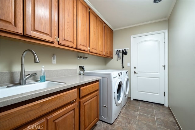 washroom with crown molding, washing machine and dryer, baseboards, a sink, and cabinet space