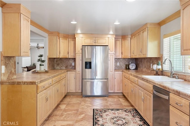 kitchen featuring light brown cabinetry, stainless steel appliances, a sink, and backsplash
