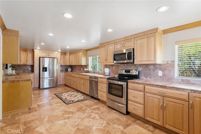 kitchen with light brown cabinetry, a sink, stainless steel appliances, recessed lighting, and tasteful backsplash