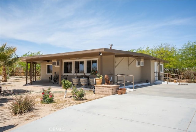 rear view of property with a ceiling fan, a patio, stucco siding, and a wall mounted AC