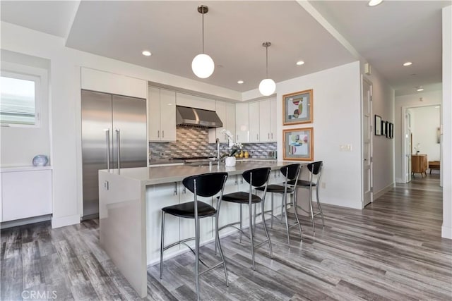 48 57th Pl, Long Beach, CA 90803 - kitchen featuring a breakfast bar area, pendant lighting, tasteful backsplash, range hood, and wood finished floors