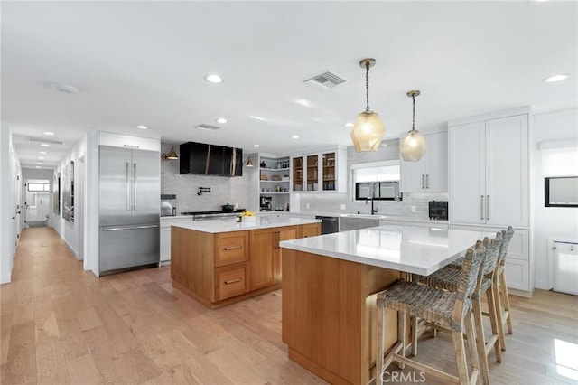 kitchen with stainless steel built in refrigerator, backsplash, a kitchen island, and visible vents